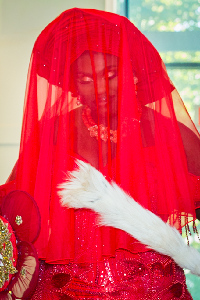 A bride in red traditional attire beneath a flowing red veil